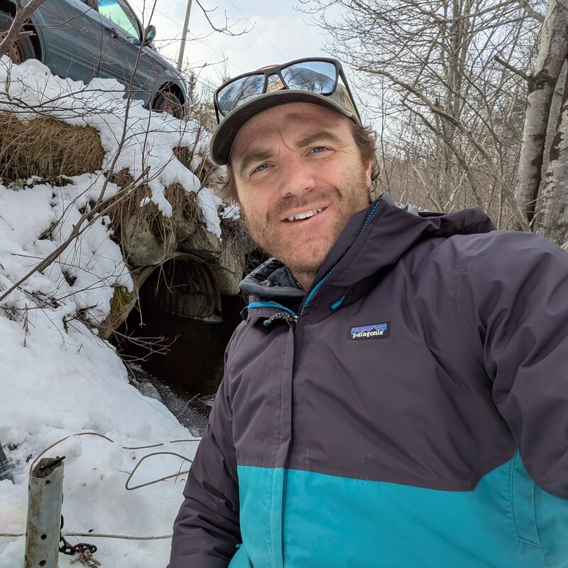 Will Daniels, aquatic biologist, beside a road culvert in winter